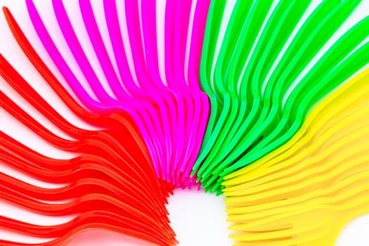 Multi colored plastic cutlery on a white background