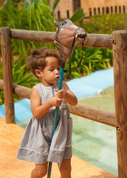 Cute Hispanic girl playing wiht an old horse toy