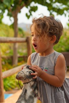 Portrait of a Hispanic girl enjoying her ride on an old horse toy