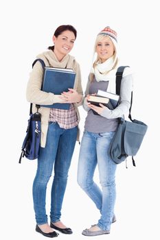 Two cute female students with books prepared for winter