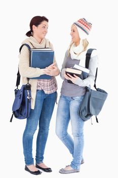 Two cute female students with books talking 