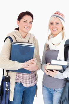 Two nice female students with books looking to camera