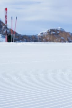 Snowcat track close-up with skiing at background