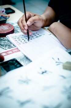 Hands writting chinese symbols on the paper, detail, close-up