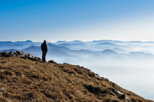 Silhouette of a man above misty mountains, blue sky, Slovakia