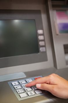 Portrait of a hand typing a PIN code at an ATM