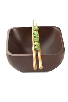 Portrait of chopsticks on a wooden bowl with green pies against white background 