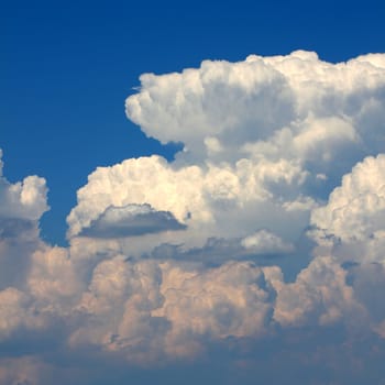 Giant cumulonimbus thunderstorm clouds erupt into the sky on a hot summer day.
