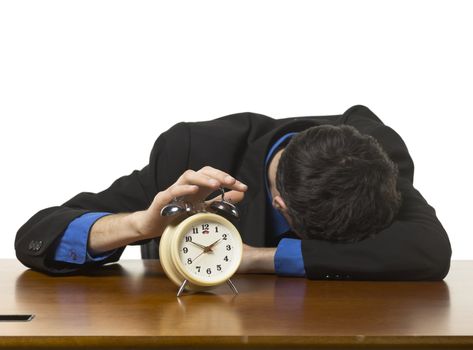 Close-up image of a sleeping businessman on his office table with alarm clock 