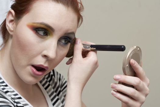 Close-up image of a beautiful woman applying herself an eye shadow makeup 