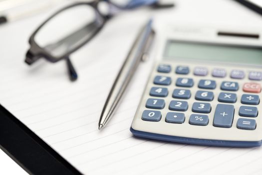 Note pad, pen, glasses and pocket calculator on a white background