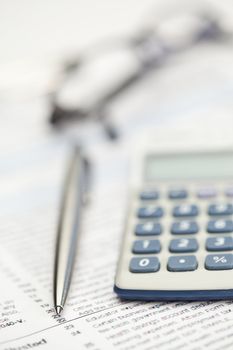 Piece of paper, pen, glasses and pocket calculator on a white background