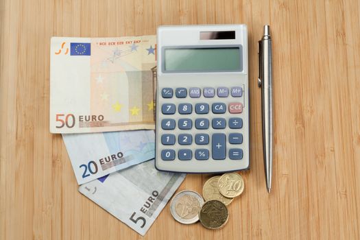 Money with pen and pocket calculator on a desk
