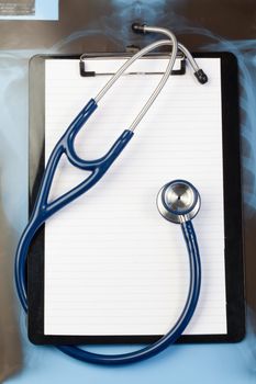 Note pad and blue stethoscope on a blue and dark background