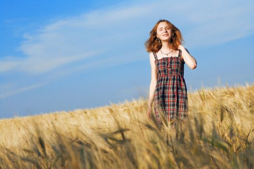 Beautfiul woman in checkered dress in a wheat field