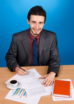 Young handsome businessman working with documents, blue background