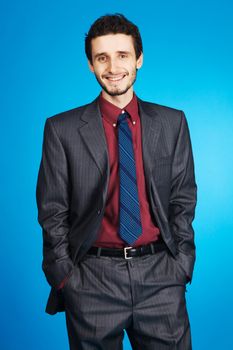 Young handsome businessman studio portrait, blue background