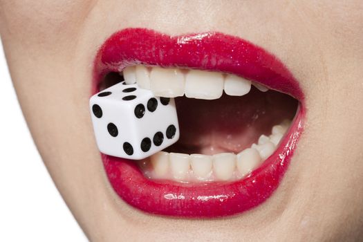 Close-up image of a woman with red lips biting dice 