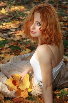 Beautiful redhead woman in yellow leaves