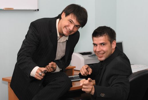 Two joyful businessmen pointing at camera
