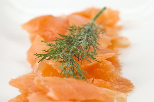 Close up image of slices of smoked salmon with dill against white background