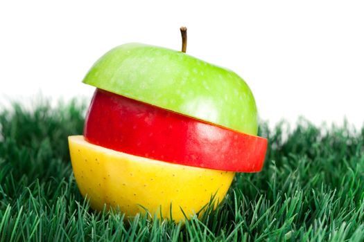 Combination of green, yellow and red apples on grass on a white background