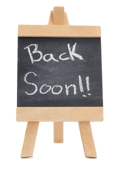 Chalkboard with the words back soon written on it isolated against a white background