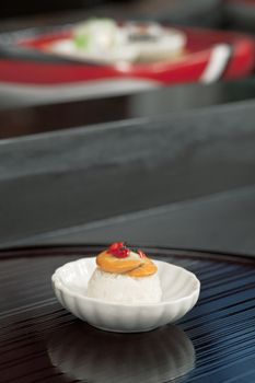 Close-up portrait of a Japanese cuisine on the white saucer with blurred maki on the background 