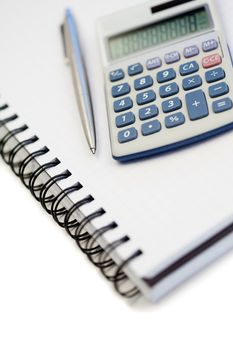 Angled notebook with pencil and pocket calculator on a white background
