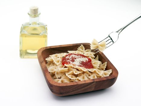 A wooden bowl full of bowtie pasta with tomato sauce and olive oil