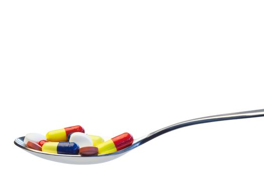 Spoon full of pills on a white background