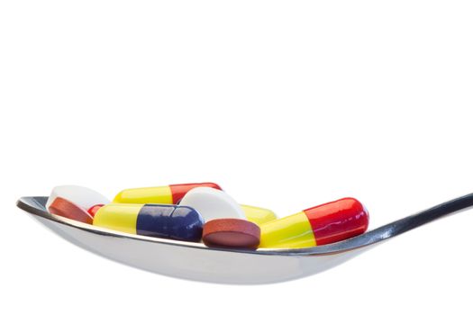 Spoon full of color pills on a white background