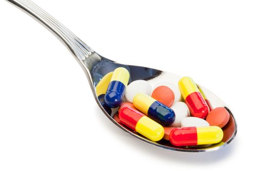 Spoon full of different kind of pills on a white background