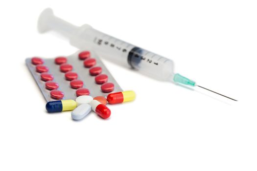 Blister strip with pills and syringe on a white background