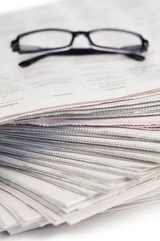 Newspapers and black glasses on a white a background