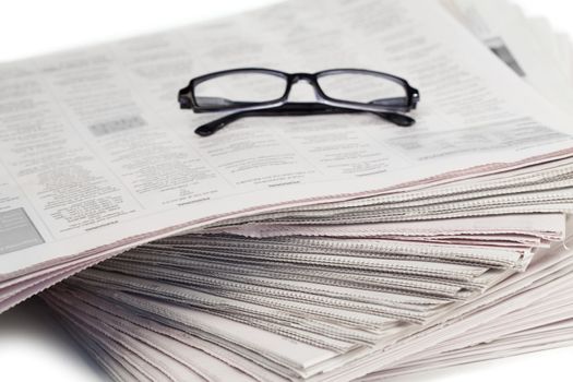 Newspapers and black glasses on a white a background