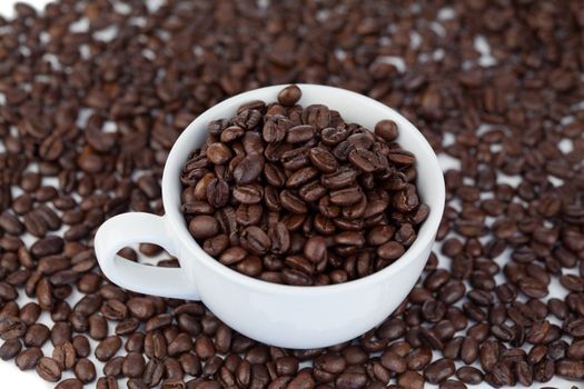 Small white cup of coffee with coffee beans on a grains background