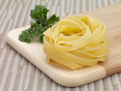 A nest of dry tagliatelle pasta on a cutting board