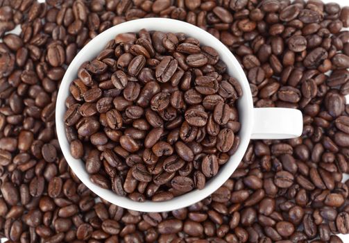 Small white cup of coffee full of coffee beans on a grains background