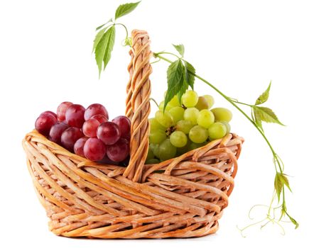 Wicker basket with grapes isolated on white background