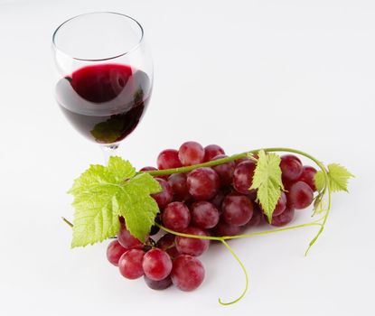 Glass of red wine with grapes, neutral background