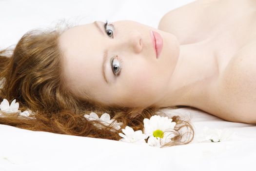 Face portrait of a beautiful model with flowers, studio photo