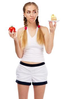 Young woman deciding on a tomato and a cake, studio photo