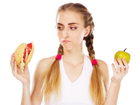 Young woman choosing between hamburger and apple, studio photo