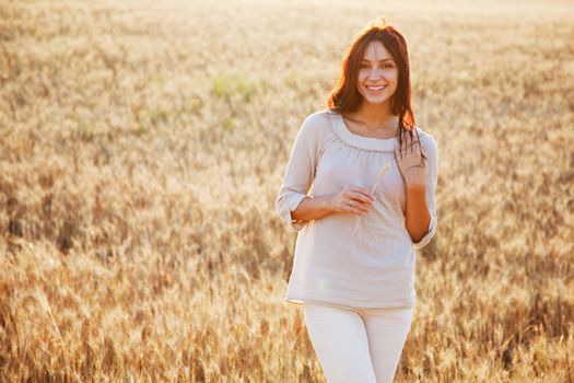 Beautiful brunette lady in wheat field at sunset