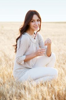 Beautiful brunette lady in wheat field at sunset