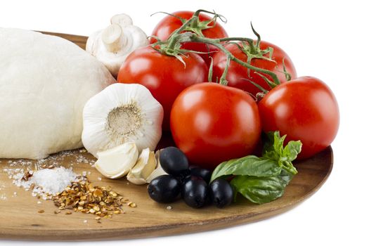 Close-up cropped shot of vegetables and other pizza ingredients on wooden plank.