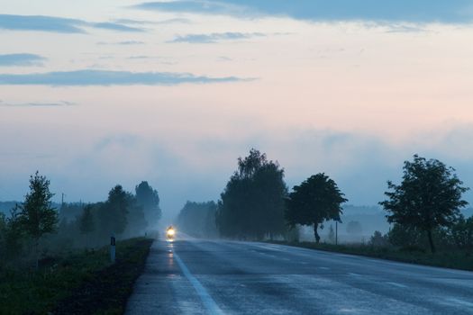 Misty rural road with a motorcyle driving along