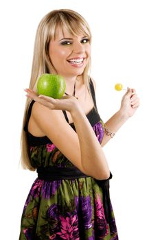 Cheerful young woman holding fresh apple and candy, isolated on white background