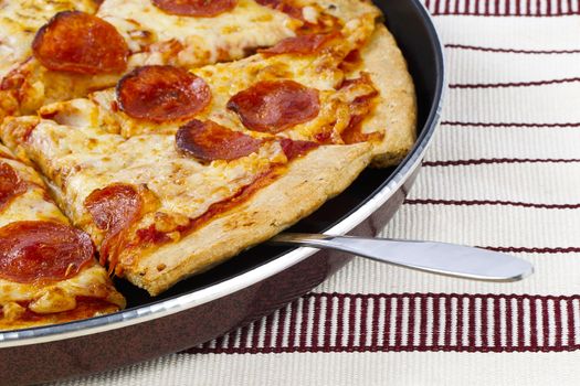A cropped image of a hot baked pan pizza on a placemat 